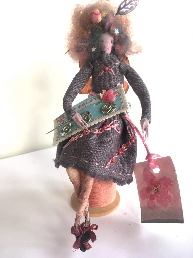 DELPHINE A 15cm high fairy who just loves to sew ! She is wearing a hand embroidered linen dress and she has silk painted butterfly wings. She is sitting on a large wooden cotton reel and on her lap she has a vintage French card of trees studs. Her fave is painted silk and her hair is brushed marino wool ( with a dried rosebud and leaf pin). £45 including UK postage ( add on £4 for international post).