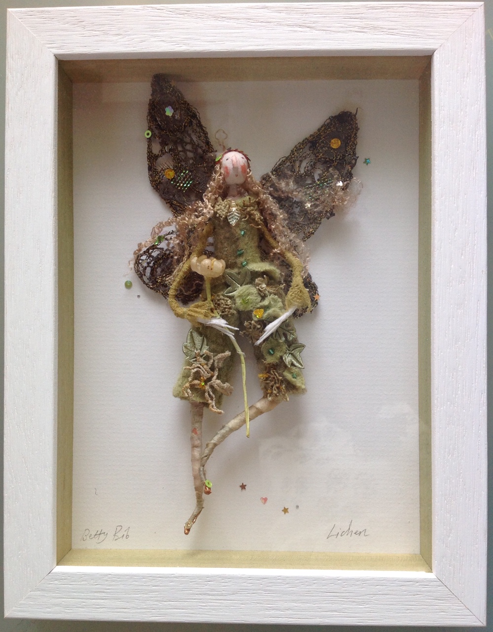 LICHEN; a 23x17.5 box framed fairy. Lichen is dressed in hand dyed ( with red onion ) clothes , trimmed with vintage lace. She has embroidered wings and is carrying a vintage wax flower. please e mail me if you would like to see her in more detail. £95 plus £3.50 postage.