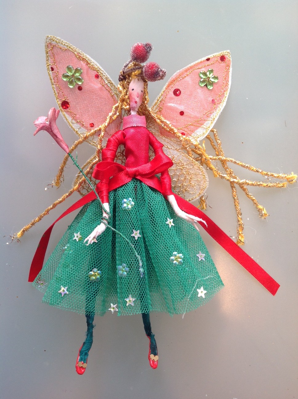 HOLLY BERRY, a 17cm fairy with a silk painted face. She is wearing a stiff net skirt with a shot metallic top and a satin ribbon at the waist. She has stiffly embroidered wings and has frosted berries in her hair. She comes in an organza bag with dried petals and a hand painted name tag. £25 plus £2 postage.