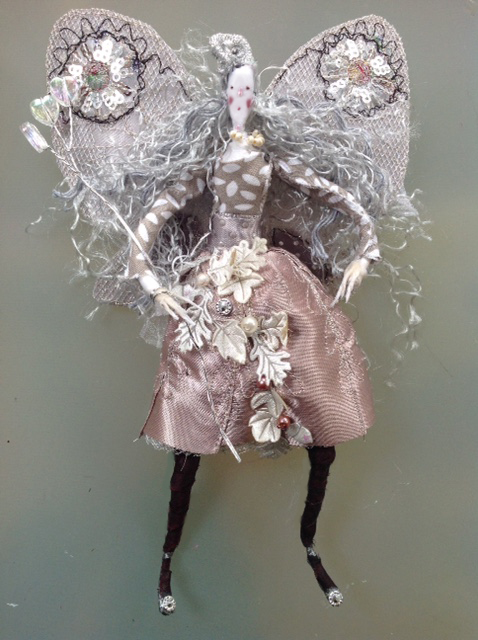 Sylvia A 17cm fairy with a silk painted head. She has stiff embroidered wings and is wearing a cotton and shiny satin dress decorated with pearls and satin leaves. She has a wired organza bow at her back. She comes in an organza bag with dried petals. £40 plus £3 p&p