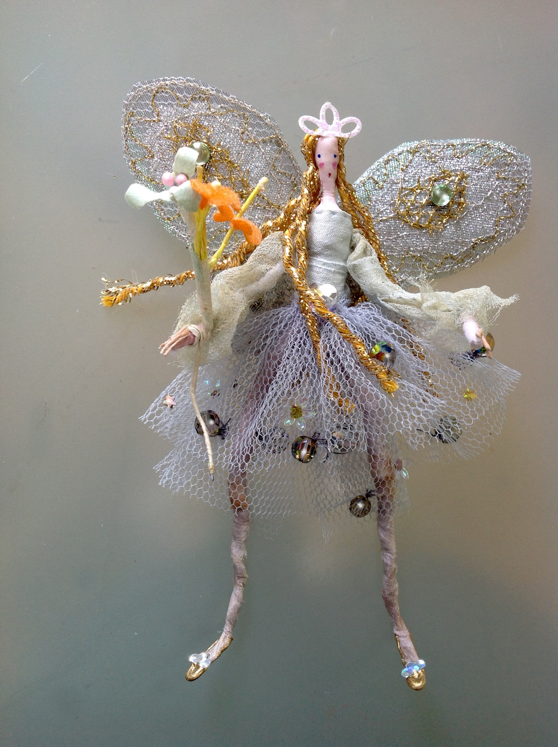 CRYSTAL An 11 cm high fairy wearing a hand dyed chiffon top and stiff netted skirt embellished with crystals and a special heart crystal at her waist. She has stiffly embroidered wings and is carrying a fabric and paper flower wand. She comes in an organza bag with dried petals. £28 plus £2 p&p.