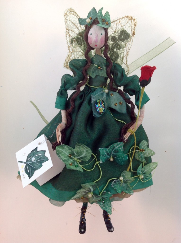 IVY A 16cm high fairy with a paper clay head , wearing a silk and organza dress embellished with hand painted ivy leaves - one of them has an iridescent glass beetle sewn onto it. She had patent boots, stiff net wings and is holding a paper rose wand. She has a hand painted name tag and comes in an organza bag with dried flowers in it. £45 plus £2 p&p.