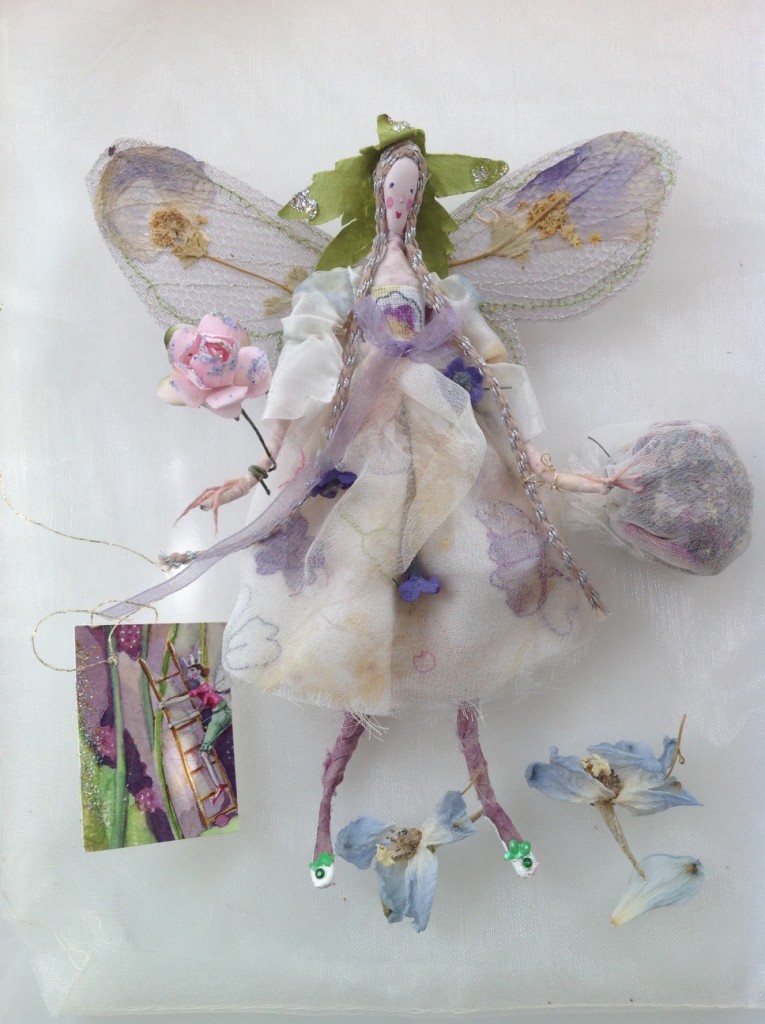 MILLEFIORE; A 15cm high fairy with a silk painted head.She is dressed in eco - printed ( impressions of verbena flower heads ) and embroidered silk chiffon. Her wings are stiffly embroidered and her wand is a paper rose. She is holding a chiffon bag of sweet smelling potpourri and she comes with a hand painted name tag and an organza bag with dried petals. £40 plus32 p&p