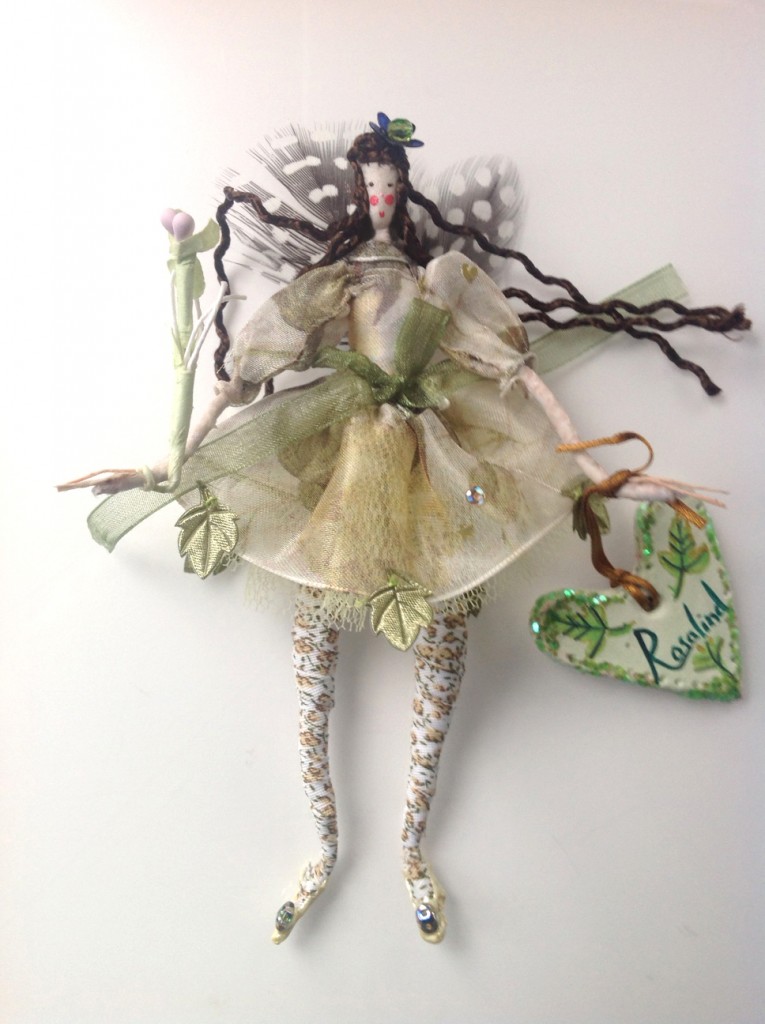 ROSALIND A 14cm Lonely Heart fairy with a silk painted head and guinea fowl feather wings. Her dress is printed organza with an organza ribbon and she has a sparkly flower in her hair. She is holding a paper flower wand and her name tag is made of clay £27 plus £2 p&p.