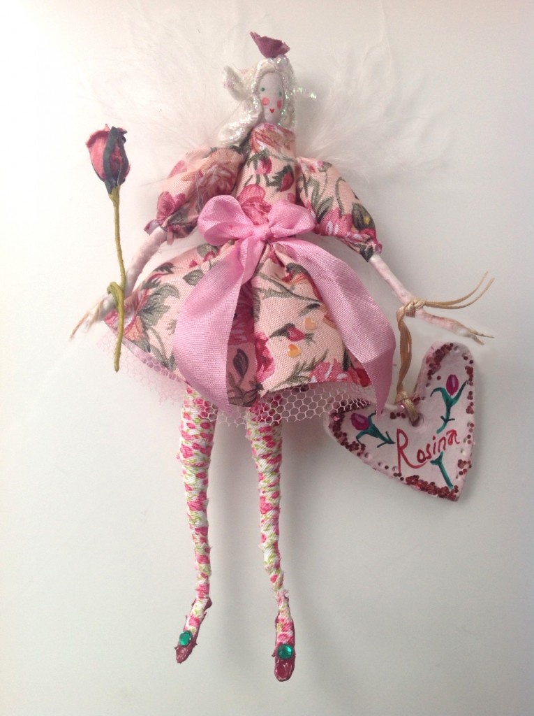ROSINA A 14cm high Lonely Heart fairy. A delicate fairy wearing a rose chintz dress with a pure silk ribbon. She has a silk painted head with iridescent hair ( a lot more sparkly than in the photo ! ) her wings are palest pink maraboa feather wings. She is holding a paper rose wand and her name tag is a painted clay. £27 plus £2p&p.
