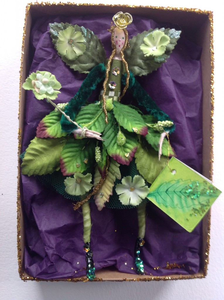 GREENSLEEVES A 15cm high fairy with a silk painted head. This Spring fairy is wearing a stiff net skirt with paper leaves, flowers, sequins and crystallised berries sewn on to it . She has silk velvet sleeves and a hand painted name tag. She comes in a Betty Bib box. £32 plus £3.50 p&p.